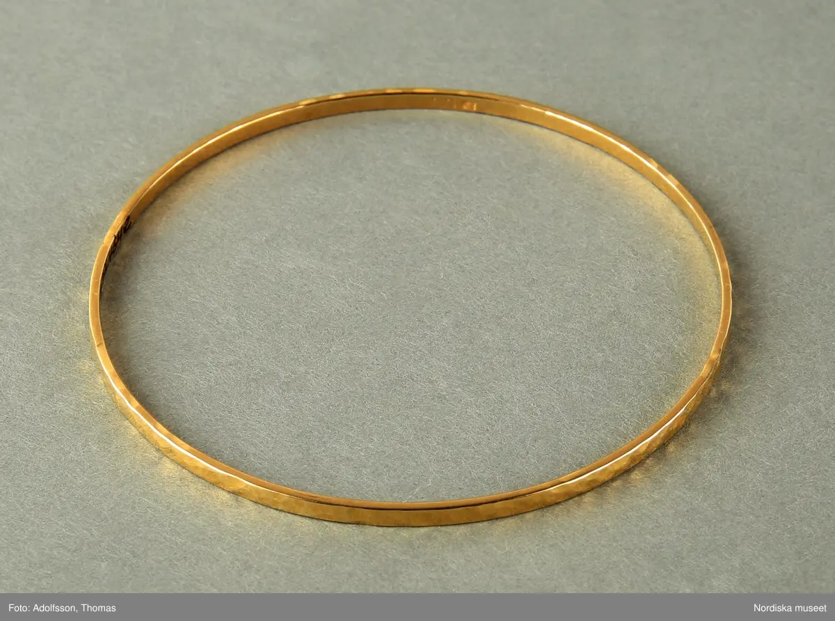 Armringar  i guld,  5 st = 2 st släta utan dekor (a-b), 1 st med dekor med tvärgående räfflor (c) och  2st  med hammrad dekor (d-e).
Samtliga armringar är stela samt utan öppning. Stämplade BJA 585. 


/Cecilia Wallquist 2019-02-15