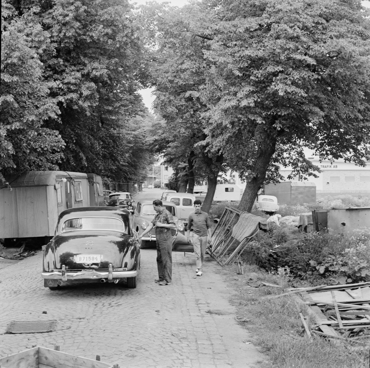 Män står på gatan invid husvagnar och bilar, Uppsala, juli 1963