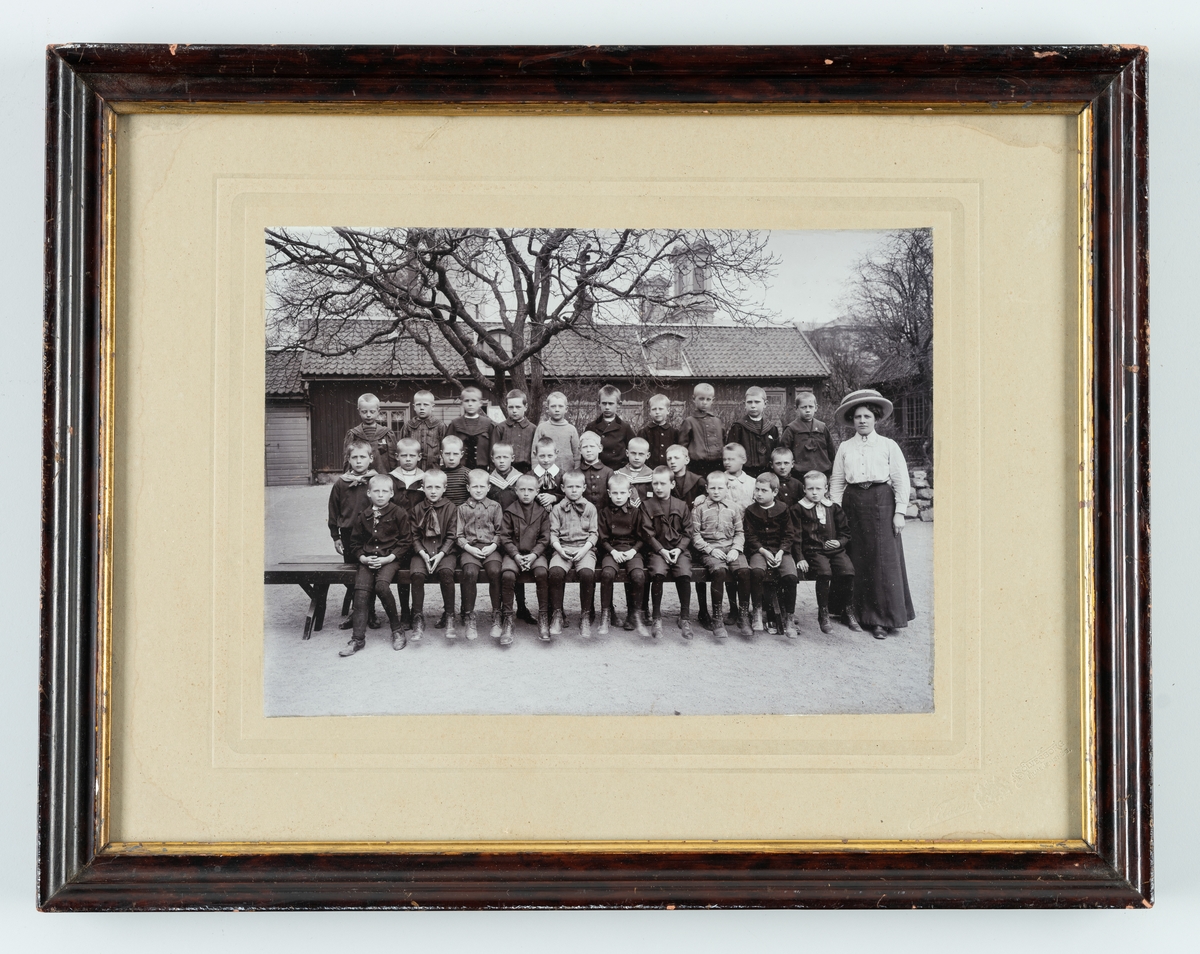 Bilden föreställer en gruppfoto av en skolklass från Amiralitetsskolan i Kungsgatan. En av pojkarna är f.d. Dir. Nils Löwenberg, Karlskrona, 2:a raden längst ut till höger. Kvinnan på bilden kan vara fröken Karlberg.