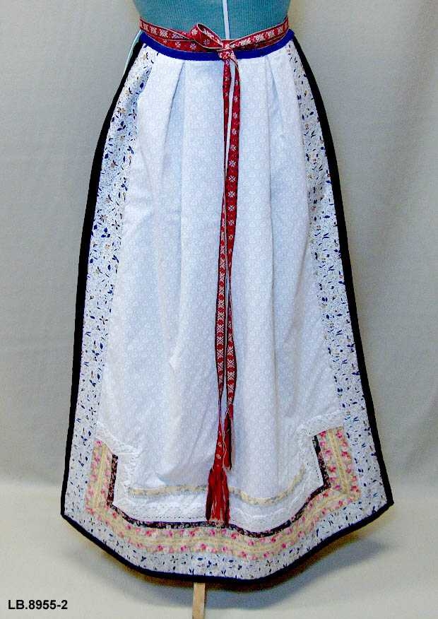 Kan brukast på begge sider, blått på eine sida, lyst på den andre. Beltet skal brettast ned, slik at det framleis viser rettsida ut, når forkleet blir bruka på den blå sida. Forkleet er kanta med blått fløyelsband. Pynta med agramaner i gull og sylv. Band til pynt, ingen broderi. 