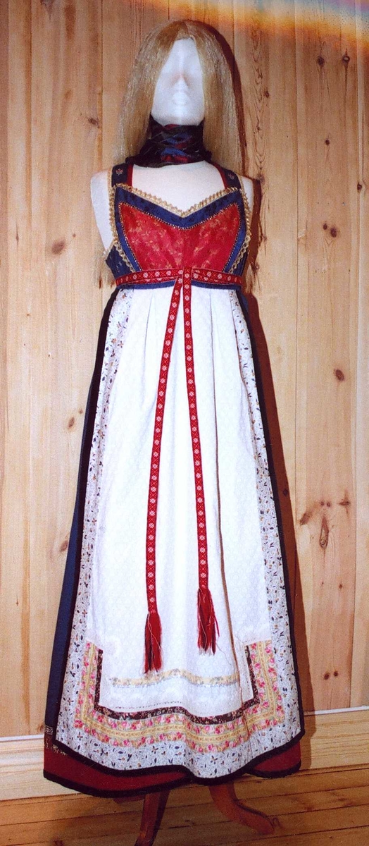 Uppluten sydd av blomstrete tøy og har perler bak. Kanta med ull og bomull. Bringekluten kan brukast på begge sider, raud på den eine, blå og lys gul på den andre. Forkleet kan og brukast på begge sider, blått på eine sida, lyst på den andre. Beltet skal brettast ned, slik at det framleis viser rettsida ut, når forkleet blir bruka på den blå sida. Forkleet er kanta med blått fløyelsband. Forkle, stakk og bringeklut er pynta med agramaner i gull og sylv. Band til pynt, ingen broderi. Drakta kan brukast i ulike samanhengar. Høgtidskledd med raud bringeklut. Med kvitt forkle er det eit endå meir høgtidsprega. Dersom ein i tillegg har la og belteklutar så er det brurestakk. Brukar ein lærbelte, er det meir kvardagplagg. Drakta kan varierast med forskjellige skjorter, sylv, plagg, og kan passe til mange typar bruk. Med den lyse sida av bringekluten fram er det meir kjøkkenfargr og meir sommarleg. Utan bringeklut kan ein bruke silkeplagg i bringa. Med  mindre pynt vert han tøffare, ein kan nesten bruke T-skjorte i staden for bunadsskjorte. 