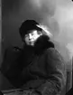Porträtt av ung kvinna i vinterkappa och hatt med fjäder. Det är möjligen Mimmi Allard.
