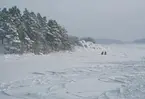 En av Waxholmsbolagets skärgårdsbåtar passerar en skoter samt motorcykelåkare ute på isen.