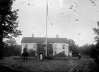 På gårdsplanen framför bostadshuset sitter en man på en häst.
Augusti 1913.