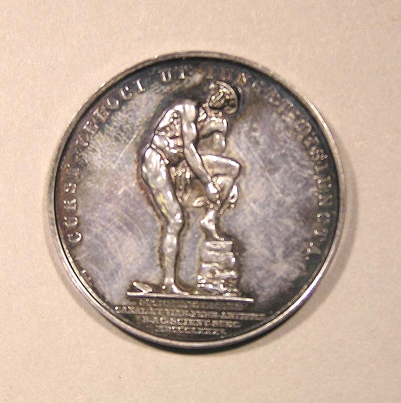 Minnesmynt av silver med profil av Nils Ericson på ena sidan och latinsk text: "Nicol. Ericson Praef. Viis Ferrat. Muniendis N. 1802 O. 1870". (Nils Ericson, chef för järnvägsbyggnaderna född 1802 död 1870).
På andra sidan syns Merkurius som fäster sina vingar på fötterna, samt texten: "Cursu veloci ut iungat disiuncta" (För att med snabbt lopp förena åtskilda platser). Under Merkurius står texten:
"Socio Meritissimo / canal et viar ferr artifici / r ac scient suec / MDCCCLXXXV (Kungliga Svenska Vetenskapsakademien för sin synnerligen förtjänte ledamot, konstruktionen av kanaler och järnvägar år 1885).