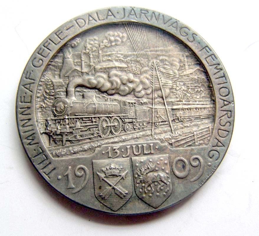 Minnesmynt av silver. På framsidan syns ett tåg draget av ett ånglok i full fart genom ett landskap, samt texten "Till minne af Gefle-Dala järnvägs femtioårsdag 13 juli 1909".
På baksidan avbildas en grankvist med kottar, samt ett vinghjul och texten "Bryta väg var af forno svensk mans största ära".
Myntet är signerat Sven Kulle på båda sidor.