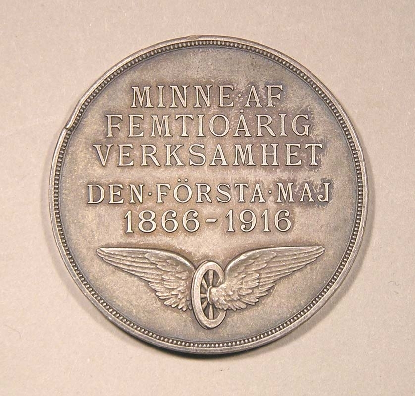 Minnesmynt av silver.
På framsidan finns ett bevingat hjul samt texten: "Minne af femtioårig verksamhet
Den första Maj
1866-1916".
På baksidan syns i mitten Ystads vapen med en grip, samt texten: "Ystad - Eslöfs Järnvägsaktiebolag".