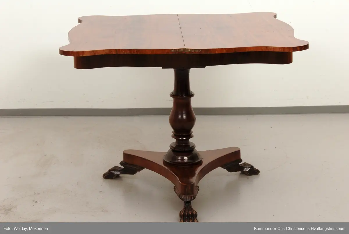 Bord hvor platen holdes oppe av dreid sokkel som hviler på fotplate med 3 utskårne bein. Bordplaten er hengslet på midten
Platen har avrundede hjørner