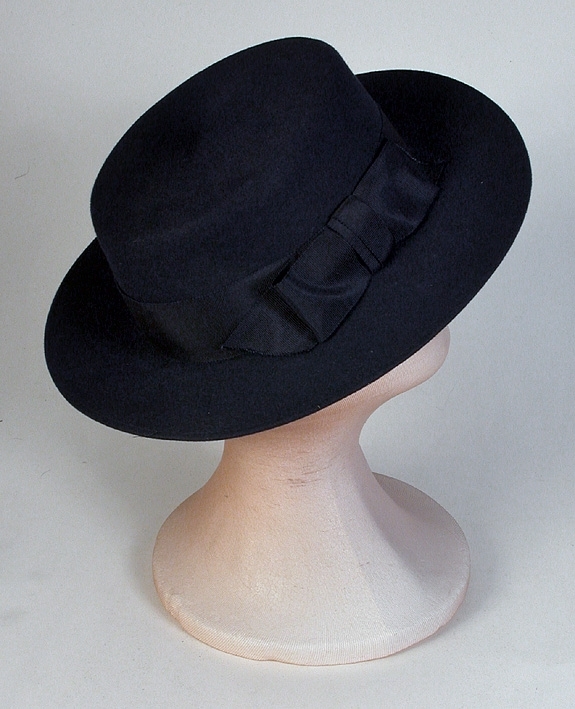 Blå filthatt, "Matros hatt". Platt kulle, lätt stukat brätte. Blått ripsband runt kullen. Enligt huvudliggaren "brederad" = kanten omvikt. 
Brätte 65 mm