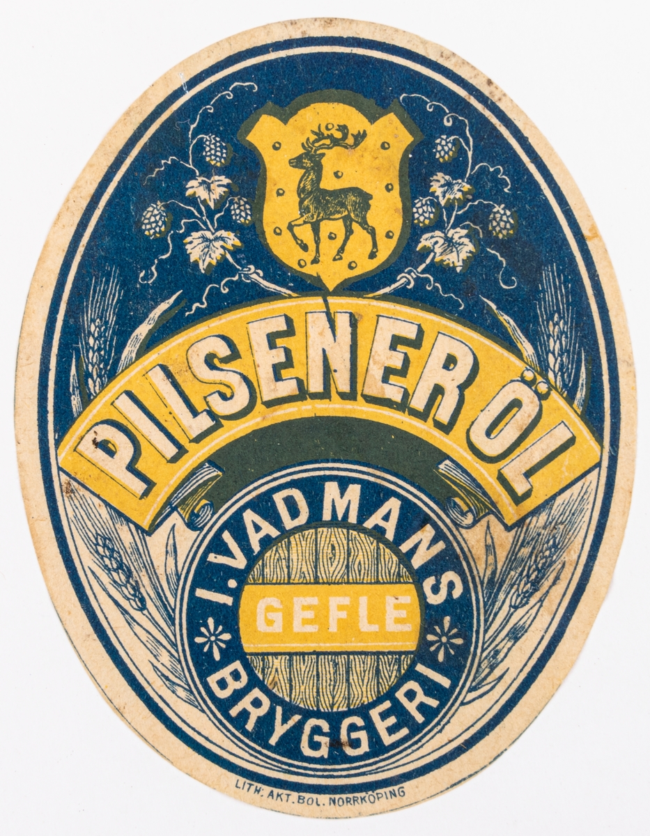 Blågul oval öletikett från Wadmans bryggeri: Pilseneröl. Motiv av korn, humlerankor och Gästriklands vapen.
Del av samling bryggerietiketter av papper, från olika bryggerier i Gävle.