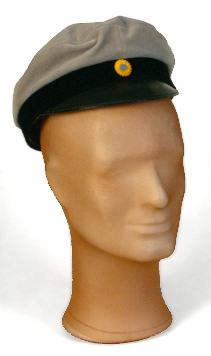 Skärmmössa av grå sammet. Platt kulle, skärm av lack. Kokard av gult och blått mitt fram.
   Mått: Runt kullen 600 mm. Höjd 70 mm. 
   Storlek: 55.