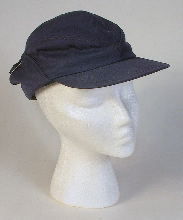 Herrmössa, skärmmössa (sport). Kilskuren kulle. Uppvikt vid sidorna. 
   Mått: Runt kullen 490 mm. Kullens höjd 170 mm. 
   Storlek: 55.