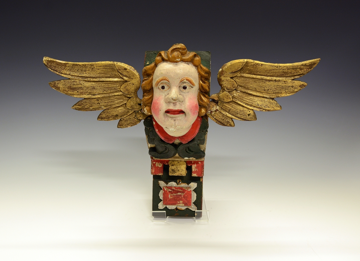 Fra protokollen (Hoel):
Kirkefigur. Vinget englehode.

Fra protokollen (Hals):
3 engleansikter (cheruber). (A-C)