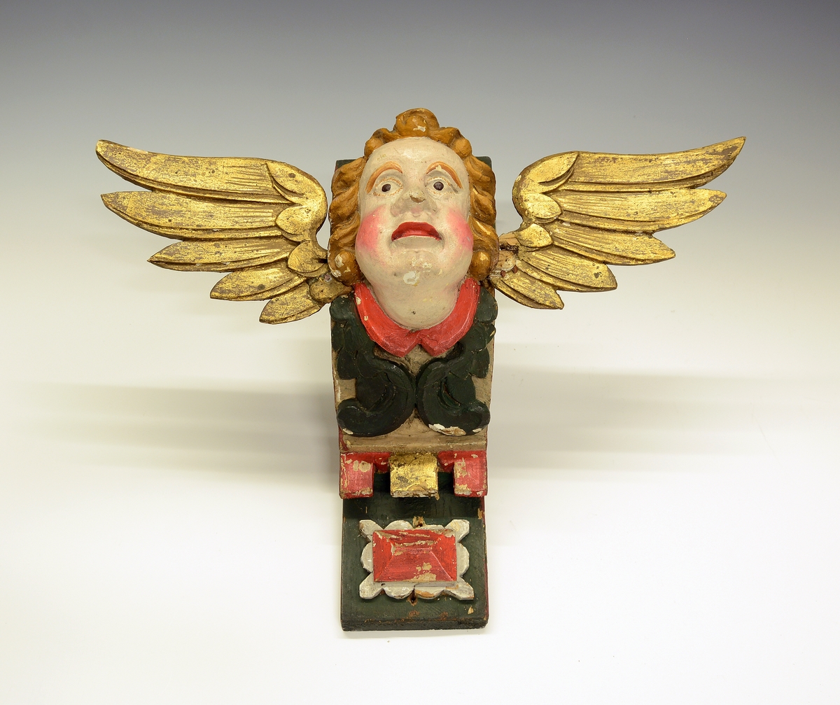 Fra protokollen (Hoel):
Kirkefigur. Vinget englehode.

Fra protokollen (Hals):
3 engleansikter (cheruber). (A-C)