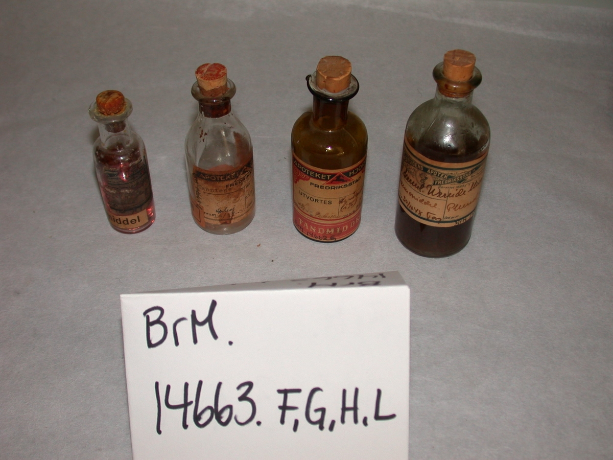 A-M: 13 stk. flasker og beholdere i glass inneholdende tannmiddel. Tannmiddel er et standard samlebegrep fra apoteket. 

A-I: inneholder innleggsmateriale til rotfyllinger
J-M: inneholder nellikolje (Eugenol). Det er dette som lager den velkjente "tannlegelukten". Denne brukes til blanding av midlertidig sement sammen med sinkoksyd. 
K = desinfeksjonsmiddel
L: sinkklorid til blanding av sement
M: til desinfeksjon (jod).