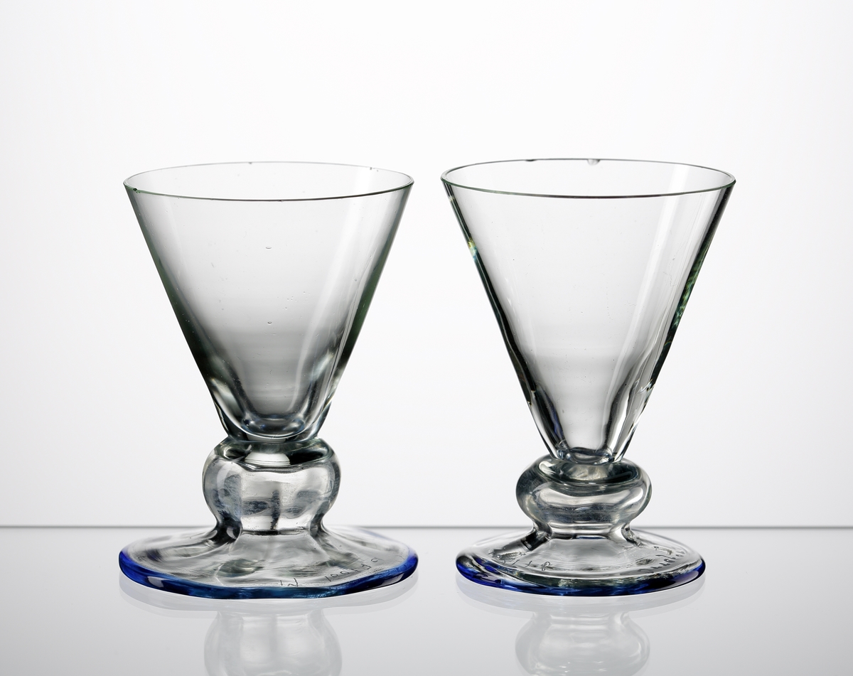 Likörglas.
Konstnär: Simon Gate.
Litet glas med v-form, stor kula innan bats och fot,
Stolpräfflad.
Sprängt, slipad kant.
Blåtonad degelfärg.
Sålt under varumärket Orrefors, tillverkat vid Sandviks Glasbruk.
Funktion: Likörglas