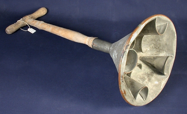 Konisk plåttratt med kopparrand vid den runt uppböjda nederkanten. Upptill ett svarvat träskaft med tvärgående handtag. Övergång mellan hatt och skaft av plåt. Inuti tratten: fastlödda halvkoniska utbuktningar i två plan, fyra i varje plan.