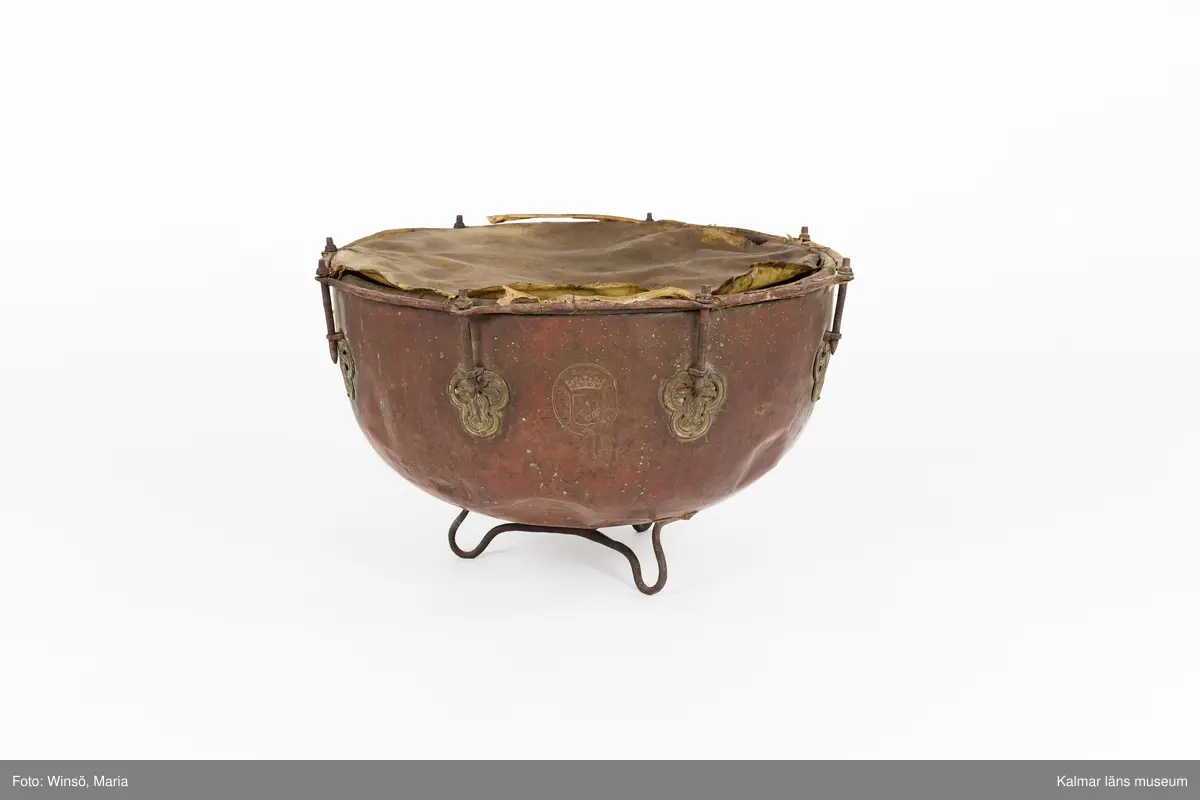 KLM 14939. Puka. Av koppar med beslag av järn och skinn på ovansidan. Står på tre korta ben formade som öglor. På utsidan skruvar och beslag formade som tulpaner. Försedd med Stålhammarska vapnet. Par med KLM 14940. Har eventuellt använts tillsammans med pukstockar KLM 14850-51.