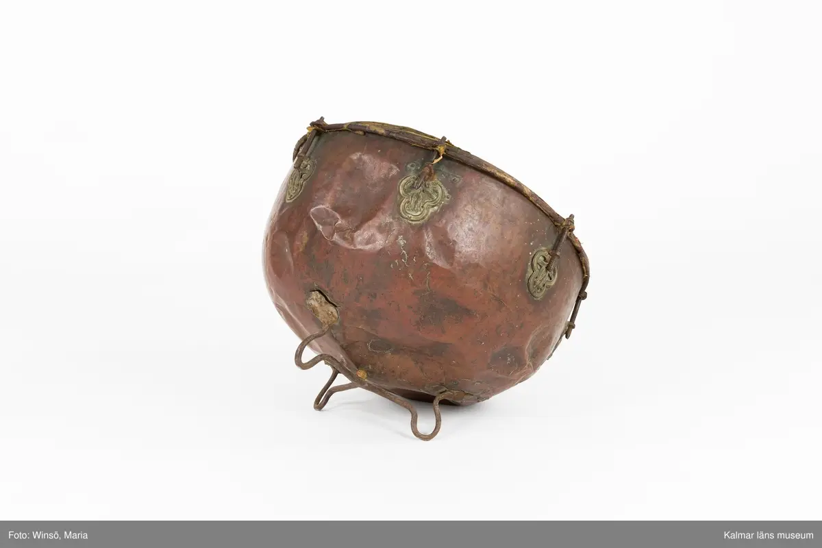 KLM 14940. Puka. Av koppar med beslag av järn och skinn på ovansidan. Står på tre korta ben formade som öglor. På utsidan skruvar och beslag formade som tulpaner. Försedd med Stålhammarska vapnet. Par med KLM 14939.  Har eventuellt använts tillsammans med pukstockar KLM 14850-51.
