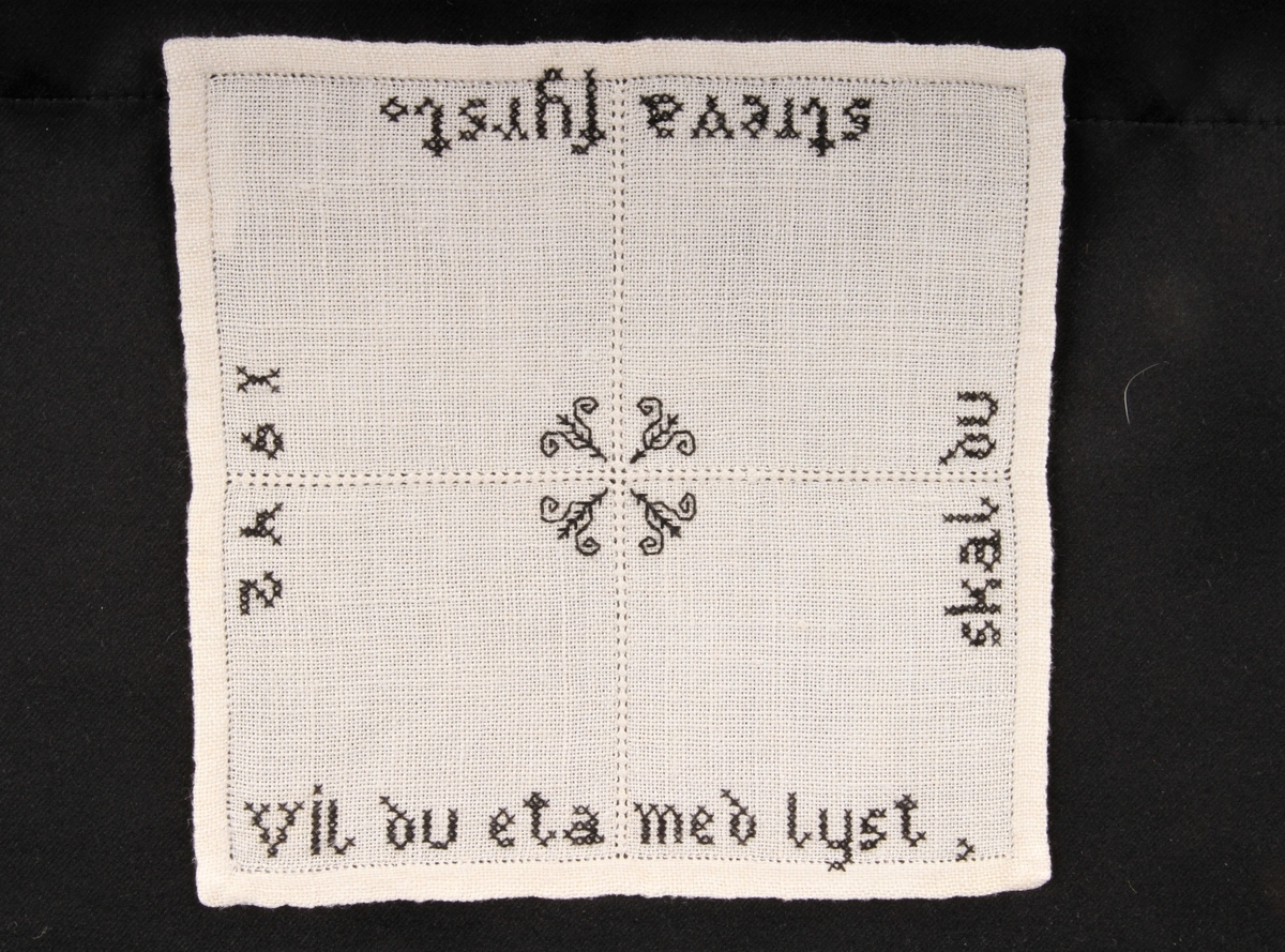 Vevd, naturfarge med svart dekor, brodert korsting, hullsøm, attersting. Border, tekst og blomster.
