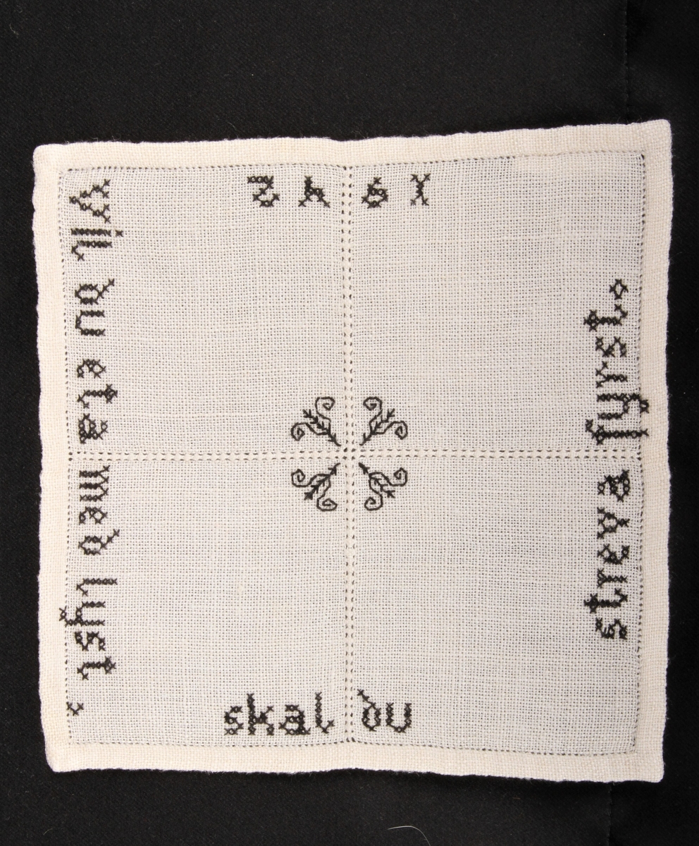 Vevd, naturfarge med svart dekor, brodert korsting, hullsøm, attersting. Border, tekst og blomster.