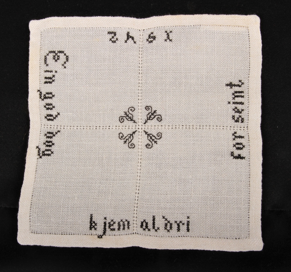 Natur bunn med svart dekor, brodert korsting, hullsøm og attersting. Border, tekst og blomster.