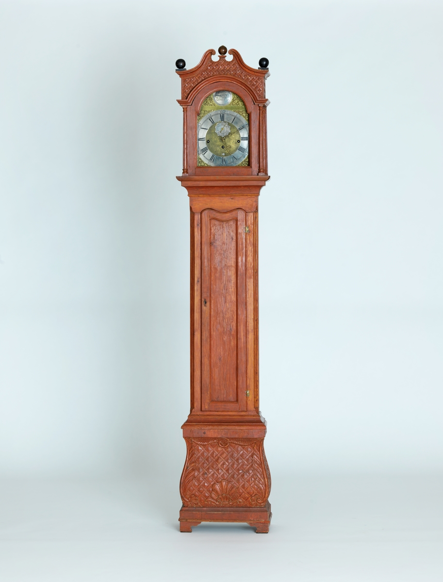 Gulvur i antatt sekundær kasse. Buet toppstykke med brutt gavl og vinduer til urverket på sidene. Rektangulær hoveddel med svungen sokkel nederst. Toppstykket dekorert med utskåret gitterverk øverst samt tre kuler på gesimsen og søyler på hver side av lysåpningen. Hoveddelen av kassen med pendeldøren er udekorert, sokkelen dekorert med utskåret gitterverk samt blader (akantus) på sidene og musling på midten nederst. Hele kassen malt ensfarget rød, kulene på gesimsen er sorte.

Urverk av messing forsynt med spillverk med elleve bjeller (visstnok til to melodier) samt én timeslagbjelle. Støpt dekor i tallskivens hjørner, hovedsakelig bladverk og c-formede ornamenter i et intrikat mønster. Midtfeltet er finhamret uten annen ornamentikk. Forsølvet timering og stjerneformet sekundring samt navneplate med signatur øverst og datoring som vises over sekstallet nederst.