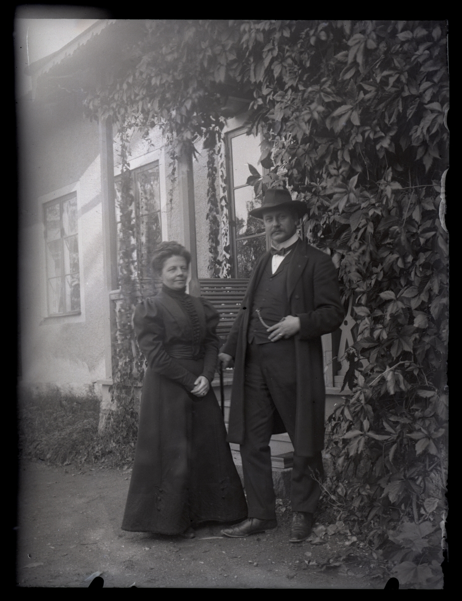 Man och kvinna utanför ett boningshus, ca 1910.