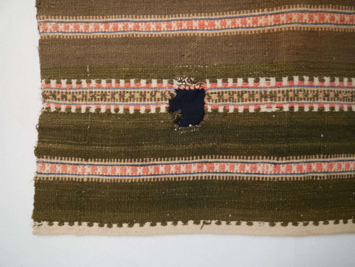 Teppet er vove i ei breidd, falda i endane. Fjølrøysåkle med to ulike mønsterrapportar.
