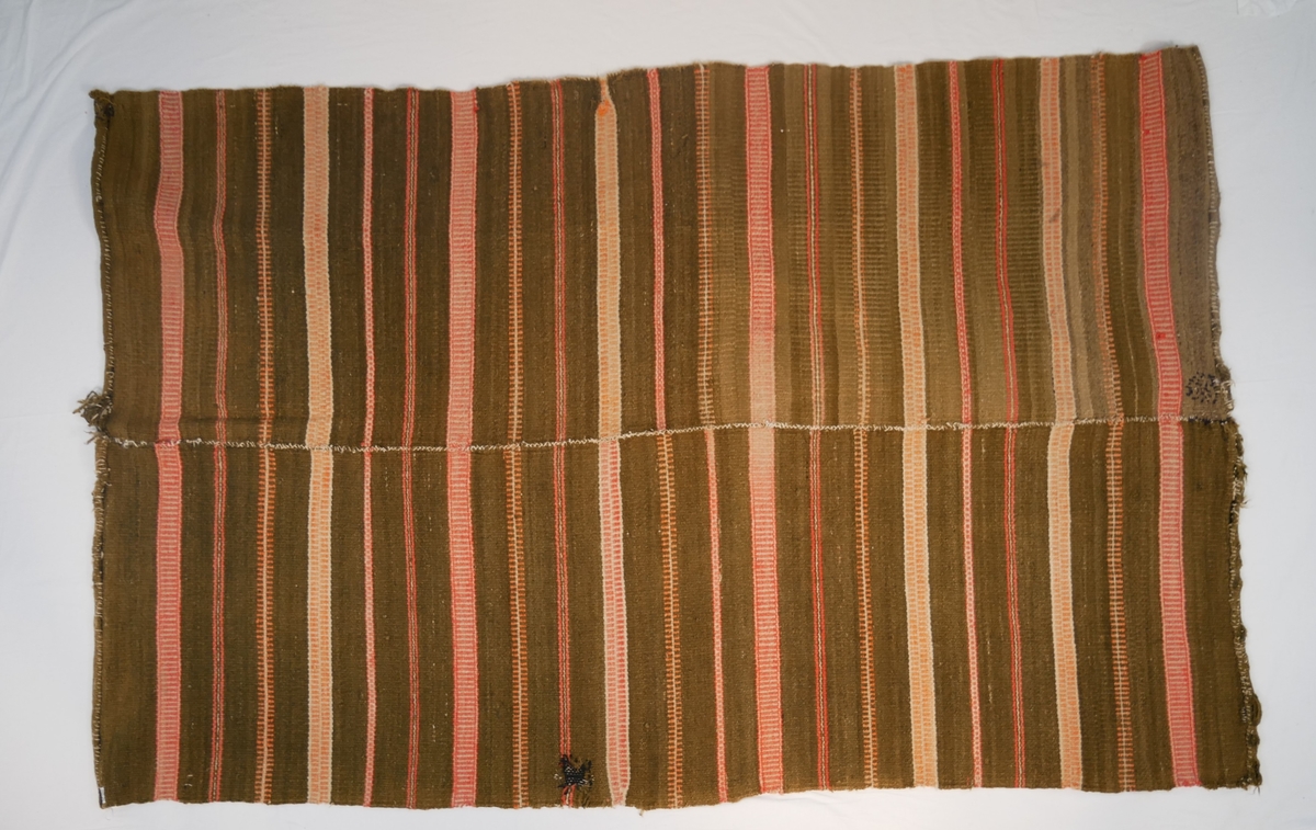 Åklet er samansytt av to lengder og falda i begge endane. Det er bøtt med mørk farge to stader.