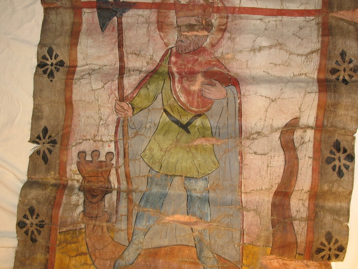 Øvre del: Olav Haraldsson med krone, kappe og øks, som står på en "underligger" formet som en drage med menneskeansikt. Nedre del: påsydde blomster