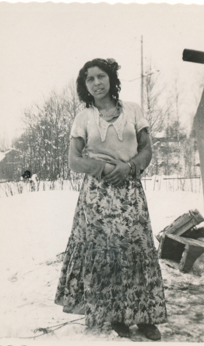 En ung kvinna avporträtterad i ett snöigt landskap. Bilden är troligen tagen i samband med en marknad i Torsby.