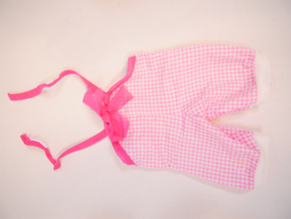 Dukkeklede som er kledd på SUM.09370. Dukkekleda består av ein kvit gensar og rosa sparkebukse. Gensaren har to trykknappar for opning/lukking bak. Ca 1/2 erme. Sparkebukse som går opp til brystkassa, med to rosa strikkband som knytast saman i nakken. Buksa er rosarutete, og har ei stor, rosa sløyfe på brystet. Kvite beinstrikk som er identiske med ermstrikka på gensaren.

Dukka vart gjeve til museet saman med fleire andre dukker med tilbehør og anna leikety (SUM.09360-09384).
