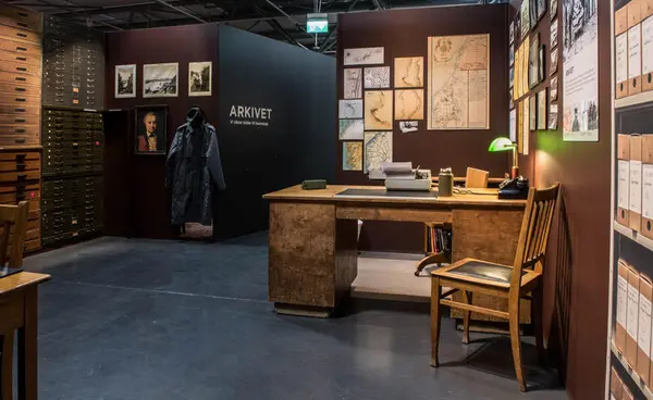 Bildeter fra Drift. Bildet viser et rom med mange skuffer, fotografier, kart o.l, samt et skrivebord.