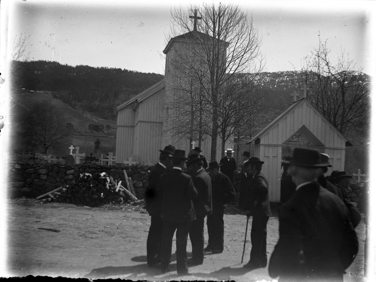 Fotosamling etter Bendik Ketilson Taraldlien (1863-1951) Fyresdal. Gårdbruker, fotograf og skogbruksmann. Fotosamlingen etter fotograf Taraldlien dokumenterer områdene Fyresdal og omegn. 
Motiv tatt utenfor kirkeporten på Moland kirke i Fyresdal.