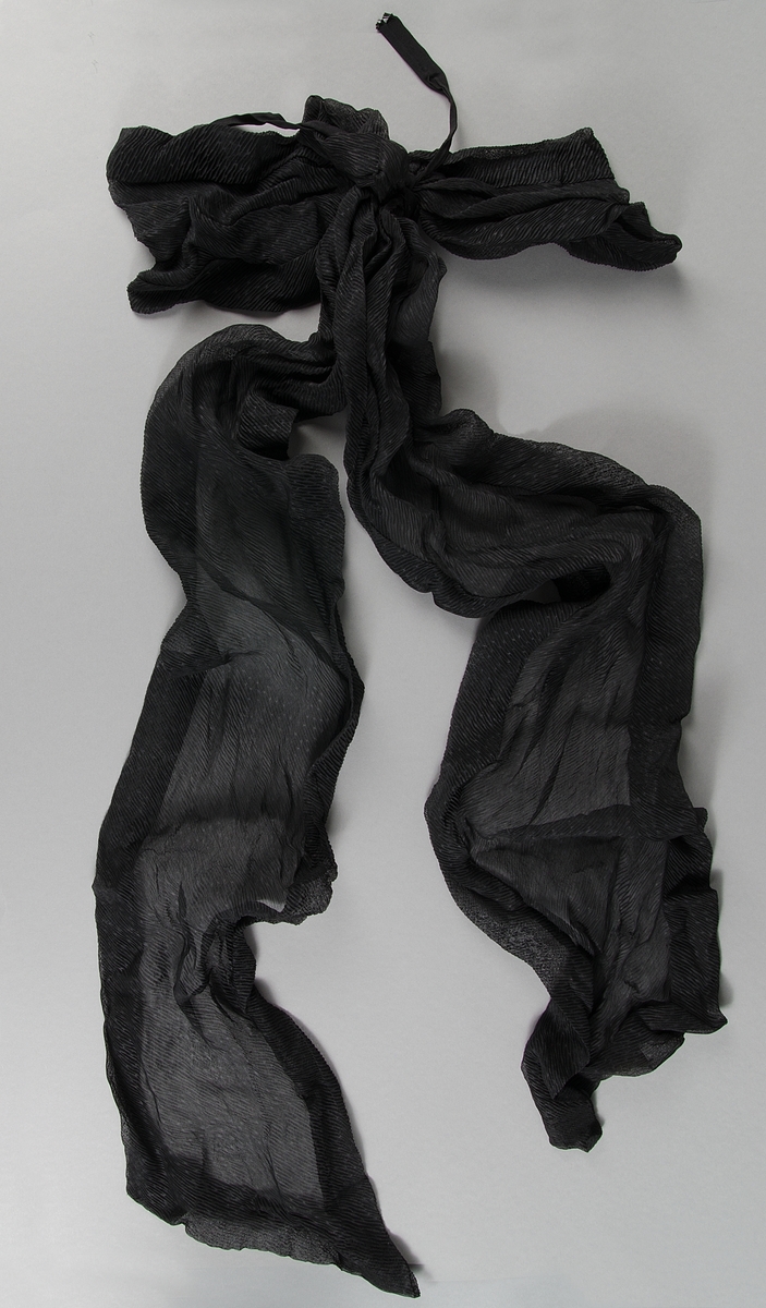 Av flaggblått ylle. Broderat med silke i schattérsöm i ett flertal färger. Moder Svea stående på jordklotet och text: Sveriges Rikssjukkassa Lokalavdelning 32 i Uppsala Stiftad 18 1/12 92. Kantat med blågula snoddar och tofsar. Fodrat med gult ylle. Trästång med svarvade knoppar. Bärstång av trä. Bärbälte av svart läder. Svart sorgflor längd ca 140 cm.