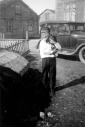 En gutt holder i hånden en hundevalp. Stedet er antakelig Sa