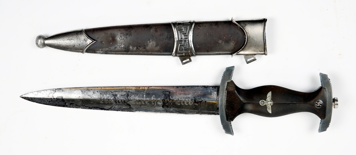 Paradedolk for SS-offiserer M/1936. Tysk. Skal angivelig ha tilhørt SS-Hauptsturmführer Karl Jonas som var sjef for SS-Grentzschutskommando på Sandbakken i Elverum. 
(SS er forkortelse for Schutz Staffel). Kjede til dolken mangler.
Knivbladet er etset inn med SS sitt æresord "Meine Ehre heisst treue".