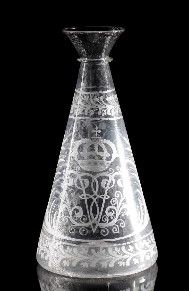 Vinkaraff, med halsring, utan propp. Graverat motiv i form av drottning Ulrika Eleonoras monogram under kunglig krona. Bred runtgående bladbård på hals och bål. Strålande nordstjärna på motsatta sidan.
Inskrivet i huvudkatalogen 1968.