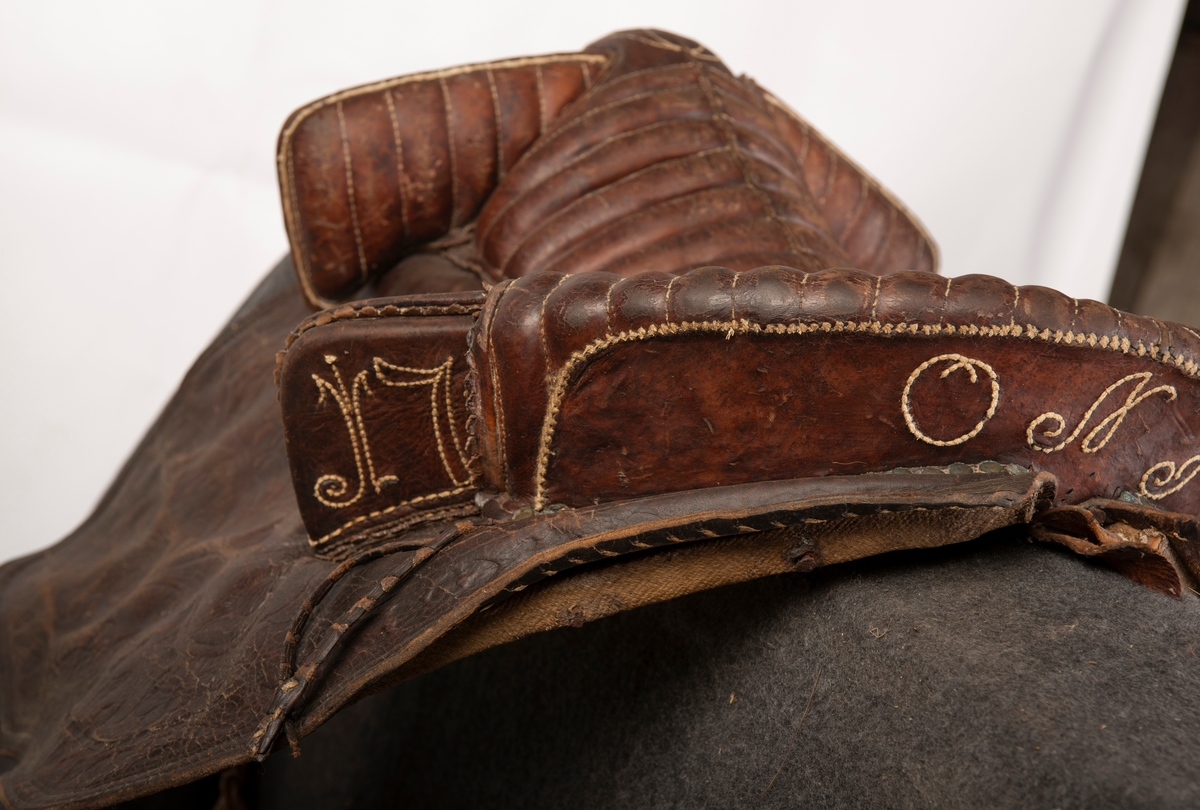 Lærtrukket sadel fra 1778. Initialene ONS brodert. Kapper med preget lær. 