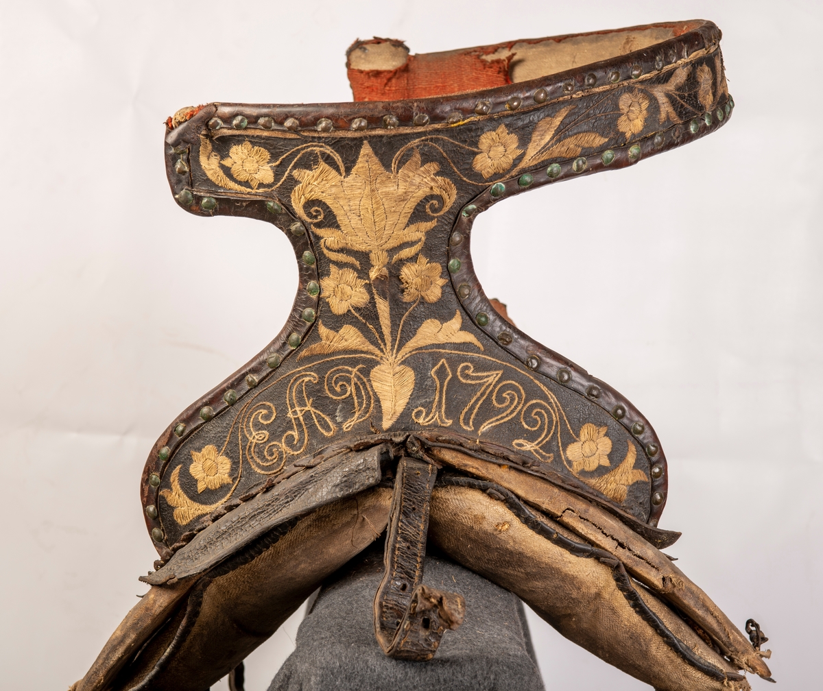 Sete av rødt ullklede reparert med stripete stoff på midten av setet. Broderte initialer EAD og 1792. Brodert lær. Mangler lærkapper.
