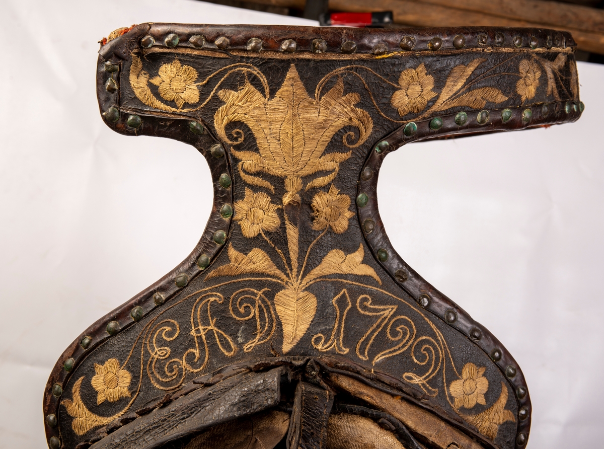 Sete av rødt ullklede reparert med stripete stoff på midten av setet. Broderte initialer EAD og 1792. Brodert lær. Mangler lærkapper.