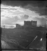 Fotografi av Brahehus slottsruin mot en mulen himmel över Vättern.