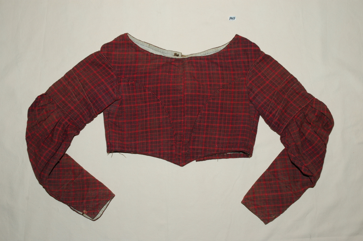 Kjoleliv av rutet bomullslerret med linfôr. Livet er håndsydd og stoffet er trolig hjemmevevd. Kjolelivet er baklukket med ti hekter og maljer. Ryggstykket har innsatt en tittekant av hovedstoffet som en figursøm. Fôret er helt. Sidesømmer av spilesøm, ellers attersting og faldesting. ERmene er satt i med åpne attersting. Sømmonnet er kastet over. Skinkeermer med tittekant i isyingssømmen, tre rader med tittekanter. Ensømserme med ni motfolder (2,5 cm breie). Sju cm bred ermesplitt som lukkes med hekter. Livet går ned i spiss midt framme. Tittekant midt framme og i en buesøm midt framme. Tittekanter langs nedrekant og halsringing. Halsringingen er oval og ermene er satt i langt utpå. (Fra registrering ved Bunad- og folkedraktrådet/Norsk institutt for bunad og folkedrakt v/Jon Fredrik Skauge, 2005, revidert v/Bjørn Sverre Hol Haugen, 2020.)