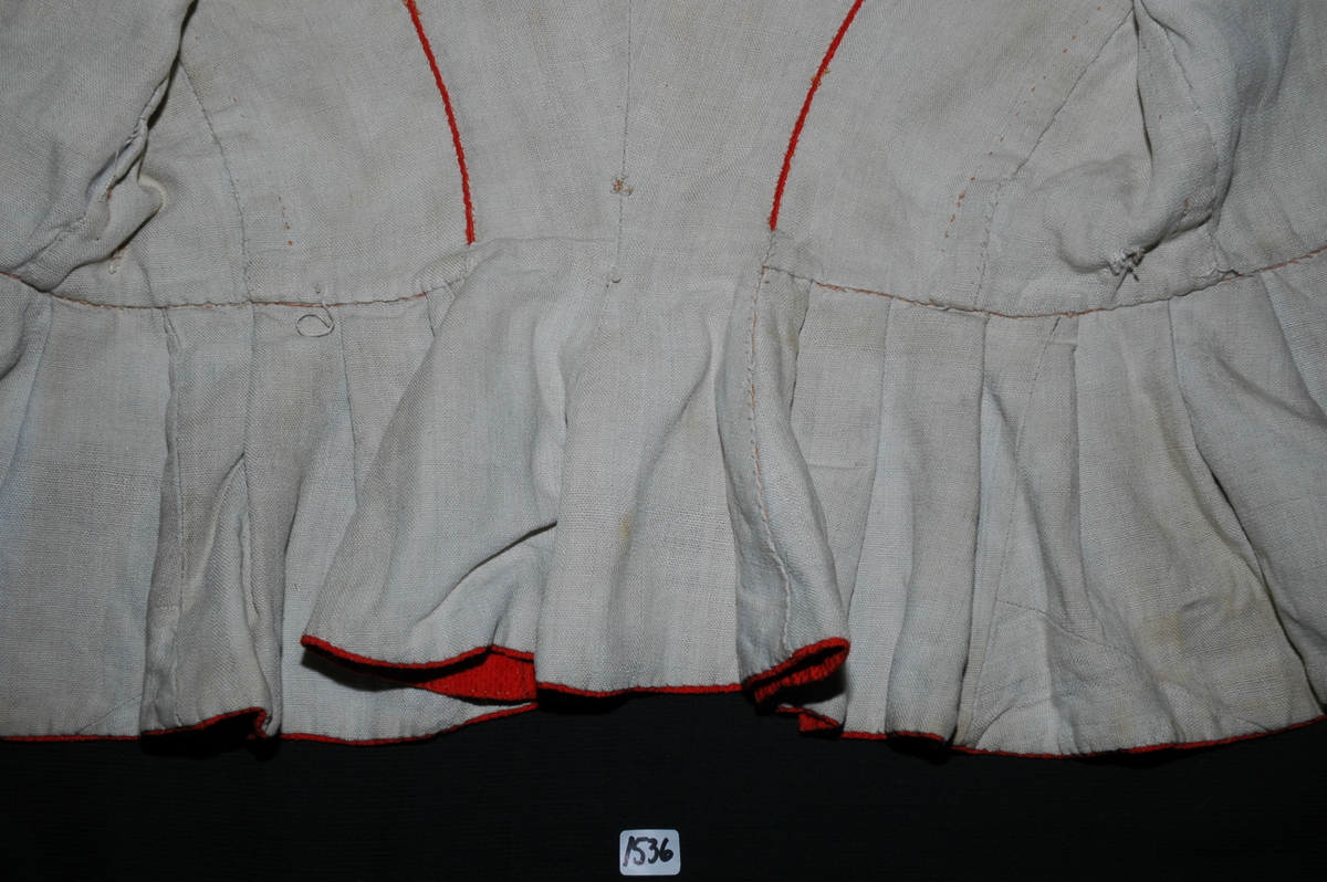 Trøye av rødt ullstoff med linfôr. Stoffet er av kamgarn og ble antageligvis solgt under betegnelsen everlasting på 1700-tallet. Produksjonssted er antageligvis England. Stoffet er i toskaft binding med flotteringer over tre tråder som gir mønstereffekt. Trøya har vært lukket med ni hekter og maljer midt framme. Snitt: Framstykkene er avdelt i midjen med kappe. Ryggstykkene går helt ned i skjøten. Kappa er foldelagt med sju folder (fra 10 cm midt framme). Foldene er 3-3,5 cm brede og 1,5 cm dype. Bua ryggsømmer sydd med spilesøm. Ryggsømmen midt bak er sydd med attersting hver for seg, men festet sammen i fôr og hovedstoff på noen steder. Det er to innsnitt under hvert herme. Ytterkantene er faldet med faldeprikkesting. Det er ekstra prikkestingsrad ved halsringing (1 cm fra ytterkant) og ved hektestillinga omlag 2 cm fra ytterkanten framme. Kappa er sydd til bolen med attersting (tre lag stoff). Fôret i bolen er bretta og lagt til og sydd ned i fôret til kappa. Kappa skrår bakover midt framme. Trange ermer sydd sammen med attersting. Sømmonnet er lagt mot bolen og fôret i bolen er lagt mot ermet og sydd til med faldesting. Skinnhemper til opphenging. Ensømserme med albuestnitt. På unerermene er det et innsnitt. Underermssømmer er sydd med attersting, stoff og fôr hver for seg (festet sammen på enkelte steder). Innsnittene er sydd med stoff og fôr sammen og lagt til en side og stukket ned, faldet til side. (Fra regsitrering ved Bunad- og folkedraktrådet/Norsk institutt for bunad og folkedrakt v/Jon Fredrik Skauge i 2005, revidert v/Bjørn Sverre Hol Haugen 2020). 