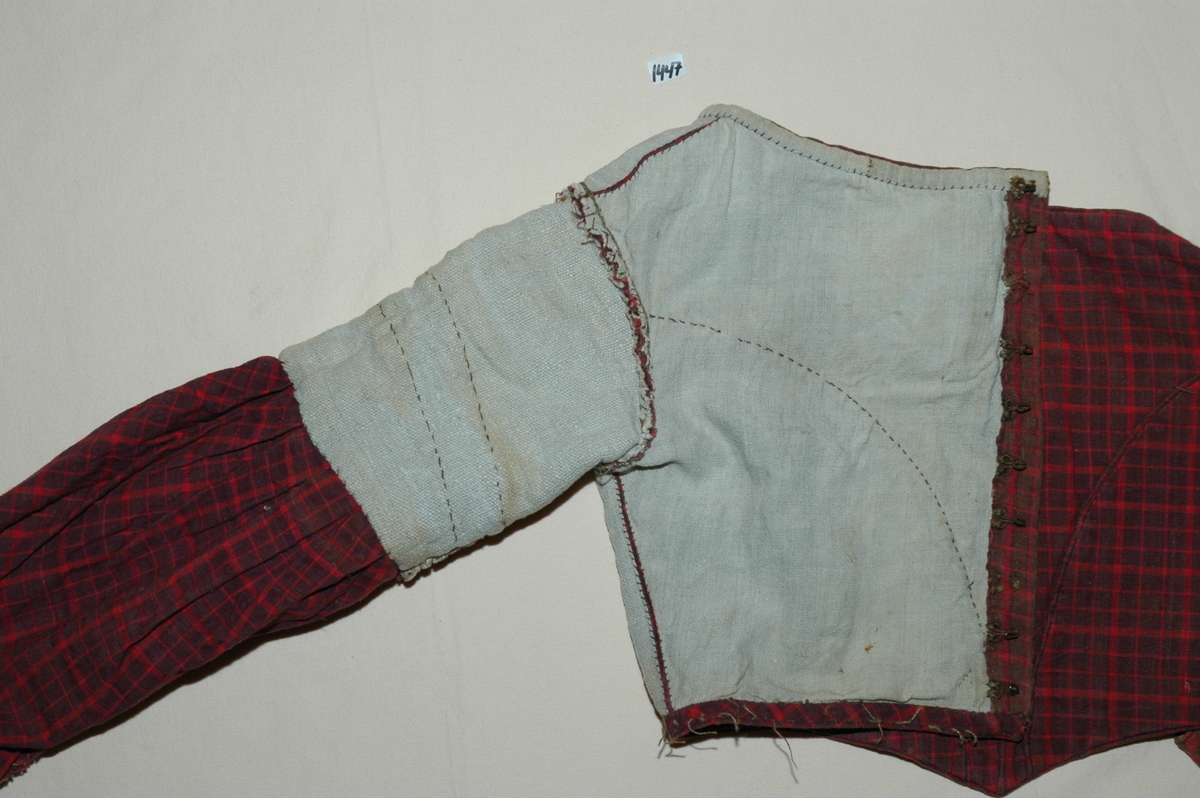 Kjoleliv av rutet bomullslerret med linfôr. Livet er håndsydd og stoffet er trolig hjemmevevd. Kjolelivet er baklukket med ti hekter og maljer. Ryggstykket har innsatt en tittekant av hovedstoffet som en figursøm. Fôret er helt. Sidesømmer av spilesøm, ellers attersting og faldesting. ERmene er satt i med åpne attersting. Sømmonnet er kastet over. Skinkeermer med tittekant i isyingssømmen, tre rader med tittekanter. Ensømserme med ni motfolder (2,5 cm breie). Sju cm bred ermesplitt som lukkes med hekter. Livet går ned i spiss midt framme. Tittekant midt framme og i en buesøm midt framme. Tittekanter langs nedrekant og halsringing. Halsringingen er oval og ermene er satt i langt utpå. (Fra registrering ved Bunad- og folkedraktrådet/Norsk institutt for bunad og folkedrakt v/Jon Fredrik Skauge, 2005, revidert v/Bjørn Sverre Hol Haugen, 2020.)