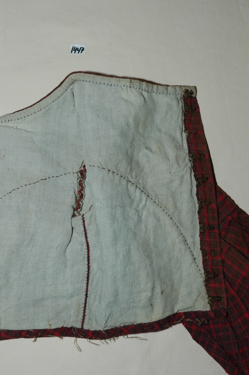 Kjoleliv av rutet bomullslerret med linfôr. Livet er håndsydd og stoffet er trolig hjemmevevd. Kjolelivet er baklukket med ti hekter og maljer. Ryggstykket har innsatt en tittekant av hovedstoffet som en figursøm. Fôret er helt. Sidesømmer av spilesøm, ellers attersting og faldesting. ERmene er satt i med åpne attersting. Sømmonnet er kastet over. Skinkeermer med tittekant i isyingssømmen, tre rader med tittekanter. Ensømserme med ni motfolder (2,5 cm breie). Sju cm bred ermesplitt som lukkes med hekter. Livet går ned i spiss midt framme. Tittekant midt framme og i en buesøm midt framme. Tittekanter langs nedrekant og halsringing. Halsringingen er oval og ermene er satt i langt utpå. (Fra registrering ved Bunad- og folkedraktrådet/Norsk institutt for bunad og folkedrakt v/Jon Fredrik Skauge, 2005, revidert v/Bjørn Sverre Hol Haugen, 2020.)