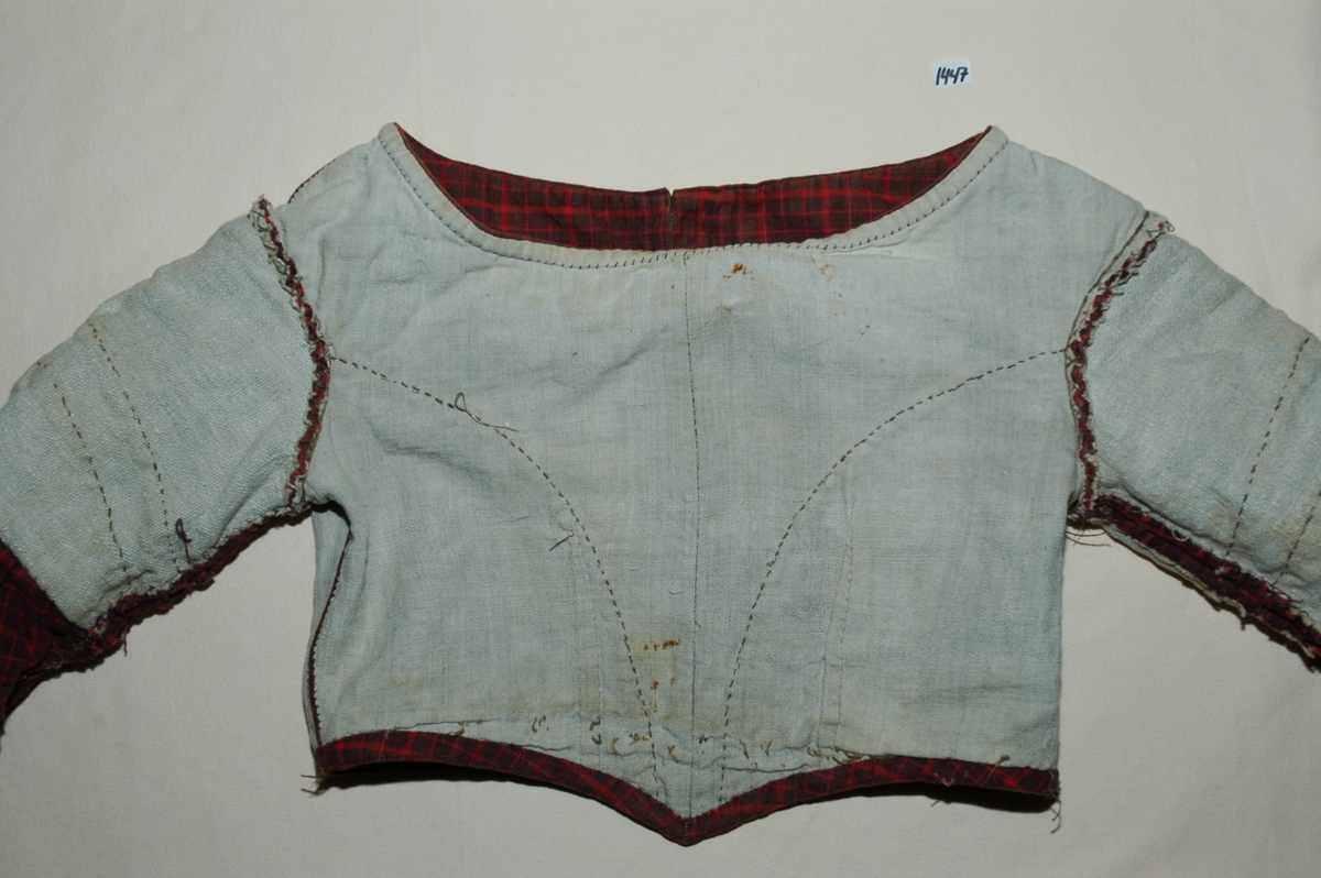 Kjoleliv av rutet bomullslerret med linfôr. Livet er håndsydd og stoffet er trolig hjemmevevd. Kjolelivet er baklukket med ti hekter og maljer. Ryggstykket har innsatt en tittekant av hovedstoffet som en figursøm. Fôret er helt. Sidesømmer av spilesøm, ellers attersting og faldesting. ERmene er satt i med åpne attersting. Sømmonnet er kastet over. Skinkeermer med tittekant i isyingssømmen, tre rader med tittekanter. Ensømserme med ni motfolder (2,5 cm breie). Sju cm bred ermesplitt som lukkes med hekter. Livet går ned i spiss midt framme. Tittekant midt framme og i en buesøm midt framme. Tittekanter langs nedrekant og halsringing. Halsringingen er oval og ermene er satt i langt utpå. (Fra registrering ved Bunad- og folkedraktrådet/Norsk institutt for bunad og folkedrakt v/Jon Fredrik Skauge, 2005, revidert v/Bjørn Sverre Hol Haugen, 2020.)