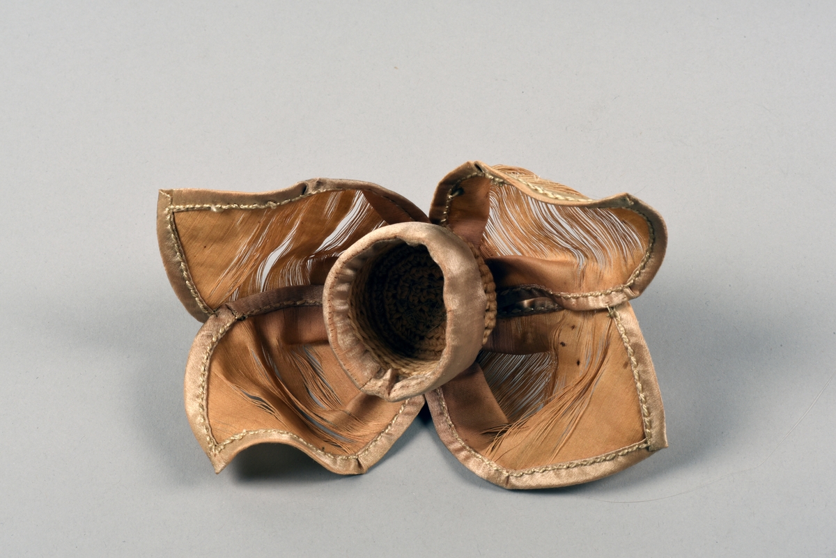 En av ett par fotogenlampor med gulmålad fot i plåt. På målningen finns tryckta stridsscener samt dekor med gotiska valv i svart. Foten är i form av en pelare på kvadratisk bas. Fotogenbehållaren är av glas och brännaren av mässing. Lampkupan är av opalfärgat glas med inslipad blomsterdekor. Högst upp ett skydd sytt i cremefärgat sidentyg, i form av en blomma.