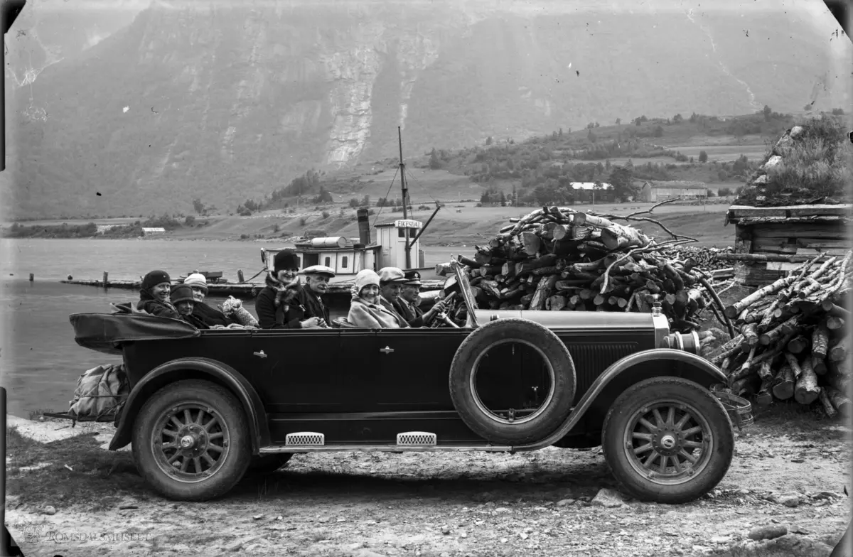 Buick 1926-modell 7-seter med en ekstra person i forsetet..Bak bilen ser vi kaia og båten D/S Eikesdal som trafikkerte Eikesdalsvatnet i mange tiår fram til begynnelsen av 1960-tallet. Da ble transporten lagt om. Båten ble erstattet av ferge som gikk på vatnet i 25-30 år. I neste fase ble det bygd vei langs vatnet og fergaruta ble nedlagt.